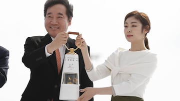El ministro surcoreano de Cultura y Deportes, Do Jong-hwan y Kim Yu-na, medallista de oro en patinaje artístico femenino en Vancouver 2010, sostienen la llama olímpica en una lámpara de seguridad a su llegada al aeropuerto de Incheon, Corea del Sur.