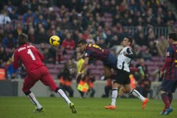 El portero brasileño del Valencia Diego Alves (c) no puede detener el balón lanzado por el delantero chileno del Barcelona Alexis Sánchez, en la jugada que ha supuesto el primer gol para el conjunto azulgrana durante el partido de la vigésimo segunda jornada de liga de Primera División, disputado esta tarde en el Camp Nou.
