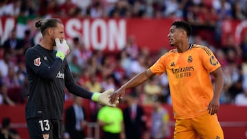 Real Madrid's English midfielder #05 Jude Bellingham (R) speaks with Sevilla's Norwegian goalkeeper #13 Orjan Haskjold Nyland during the Spanish league football match between Sevilla FC and Real Madrid CF at Ramon Sanchez Pizjuan Stadium in Seville on May 18, 2025. (Photo by CRISTINA QUICLER / AFP)