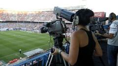 Dos operadores de c&aacute;mara en un campo de f&uacute;tbol.