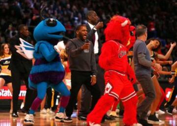 El actor Anthony Anderson, Dikembe Mutombo y el televisivo Jon Stewart bailan junto a las mascotas durante la celebración del concurso de triples.