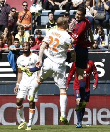 El delantero de Osasuna Oriol Riera (d) cabecea el balón ante el defensa francés del Valencia Jérémy Mathieu (2d).