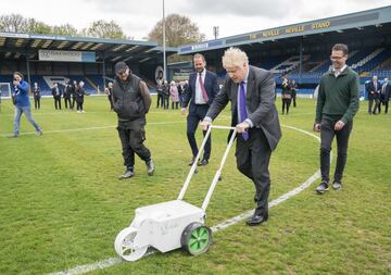 El primer ministro británico, Boris Johnson, visitó recientemente Bury, en Gran Mánchester y pasó por el Gigg Lane, el estadio del Bury FC, mítico equipo que formó parte de las categorías profesionales del fútbol inglés desde 1894 hasta 2019. En la imagen, Johnson pinta la línea blanca que delimita el círculo central del terreno de juego