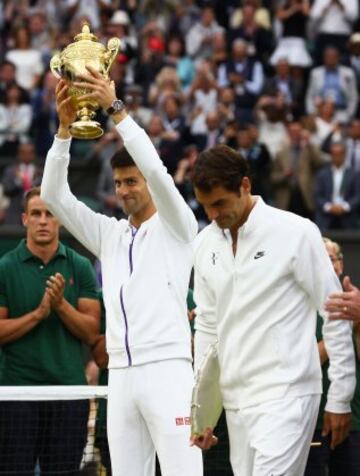 Novak Djokovic alza el trofeo que le acredita como ganador del Campeonato de Wimbledon ante Roger Federer.