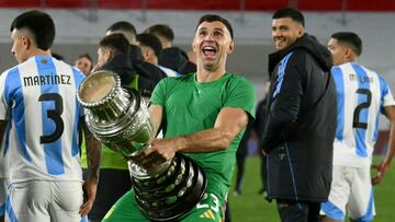 (FILES) Argentina's goalkeeper Emiliano Martinez gestures as he celebrates with a replica of the Copa America trophy after winning the 2026 FIFA World Cup South American qualifiers football match between Argentina and Chile at the Mas Monumental stadium in Buenos Aires on September 5, 2024. The Argentine Football Association (AFA) confirmed on September 28, 2024, in a statement that FIFA sanctioned goalkeeper Emiliano 'Dibu' Martinez with a two-match suspension for "offensive behavior" during the World Cup-2026 qualifiers against Chile and Colombia played in September. (Photo by Luis ROBAYO / AFP)