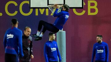 Gerard Piqu&eacute; se cuelga del aro de la canasta que hay en el campo de entrenamiento del Barcelona en la sesi&oacute;n de ayer.