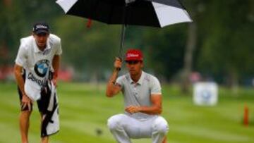 Rafa Cabrera Bello, bajo un paraguas y junto a su caddie en el torneo de M&uacute;nich. 