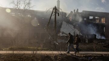 BAKHMUT, UKRAINE - DECEMBER 14: Residents walk past a smouldering building that was hit by recent Russian shelling on December 14, 2022 in Bakhmut, Ukraine. Russia continues its campaign to seize Bakhmut, Donetsk region, in what many analysts regard as an offensive with more symbolic value than operational importance for Russia. In a recent intelligence report, the British ministry of defense said Russia would try to encircle the city. (Photo by Chris McGrath/Getty Images)