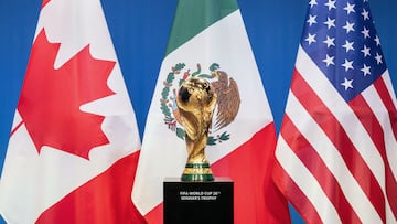 Fotografía de las banderas de Canadá, México y USA, con el trofeo de la Copa Mundial de la FIFA.