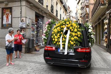 Dos mujeres aplauden al coche fúnebre en el que se encuentra el féretro con los restos del ciclista Federico Martín Bahamontes durante su camino al cementerio.