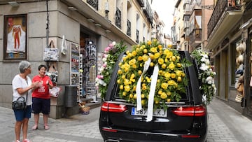Dos mujeres aplauden al coche fúnebre en el que se encuentra el féretro con los restos del ciclista Federico Martín Bahamontes durante su camino al cementerio.