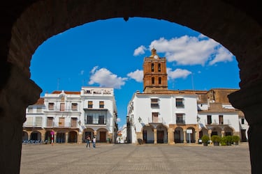 Zafra, en la provincia de Badajoz, es una elegante ciudad conocida como "Sevilla la Chica" por su notable parecido y riqueza arquitectónica. Declarada Conjunto Histórico-Artístico, su corazón lo forman la Plaza Grande y la Plaza Chica, dos plazas porticadas que se conectan a través del popular "Arquillo del Pan" y son el centro de la vida social y comercial. Sobre el casco urbano destaca el imponente Palacio de los Duques de Feria, una fortaleza señorial del siglo XV convertida hoy en Parador Nacional de Turismo, que es uno de los símbolos de la ciudad. El legado de su pasado como villa nobiliaria se aprecia en sus numerosas iglesias y conventos, como el de Santa Clara, y en las mansiones blasonadas que adornan sus calles estrechas.