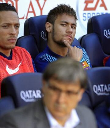 El delantero brasileño Neymar Jr., del FC Barcelona, en el banquillo junto al defensa brasileño Adriano Correia (i), y el entrenador Gerardo "Tata" Martino (c, delante), al inicio del partido ante el Osasuna de la vigésimo octava jornada de la Liga de Primera División.