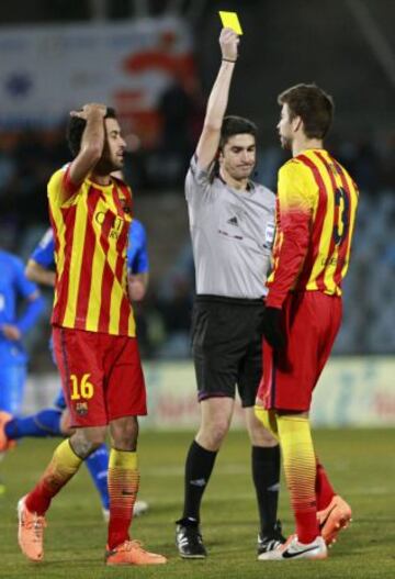El colegiado Alberto Undiano Mallenco muestra la cartulina amarilla al defensa del Barcelona Gerard Piqué en el partido ante el Getafe, de la decimoséptima jornada de la liga en Primera División que se disputa esta tarde en el Coliseo Alfonso Pérez.