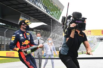 Max Verstappen moja con champán a un cámara de televisión. 