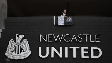 A Newcastle United football club supporter stands with a flag above the club logo at their stadium St James' Park in Newcastle upon Tyne in northeast England on October 8, 2021. - A Saudi-led consortium completed its takeover of Premier League club Newcastle United on October 7 despite warnings from Amnesty International that the deal represented "sportswashing" of the Gulf kingdom's human rights record. (Photo by Oli SCARFF / AFP)