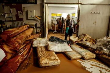 Una mujer realiza labores de limpieza en el interior de la tienda de indumentaria fallera Bordados Casti tras los efectos de la DANA en Picanya, Valencia.