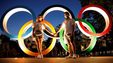 A couple poses for photos in front of the Olympic Rings outside the Olympic Stadium in Tokyo, Japan.