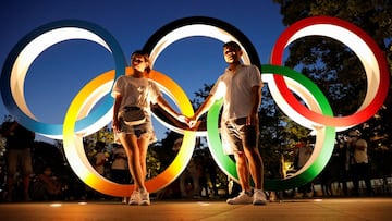 A couple poses for photos in front of the Olympic Rings outside the Olympic Stadium in Tokyo, Japan.