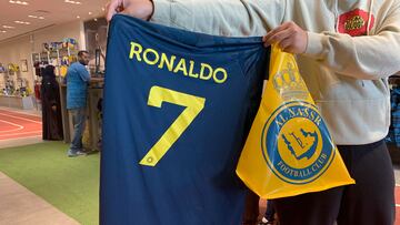 A fan holds t-shirt bearing the name Ronaldo and number 7, at the Saudi Al Nassr FC shop in the Saudi capital Ryadh, on December 31, 2022. - Cristiano Ronaldo on December 30 signed for Al Nassr of Saudi Arabia, the club announced, in a deal believed to be worth more than 200 million euros. The 37-year-old penned a contract which will take him to June 2025. (Photo by Fayez Nureldine / AFP)