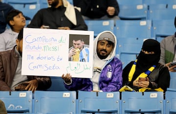 Un aficionado con una pancarta dedicada a Messi y con una foto del argentino besando el trofeo de la Copa del Mundo.