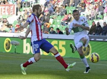 El defensa del Atlético de Madrid Juanfran Torres lucha un balón con el delantero brasileño del Elche, Jonathas de Jesus.