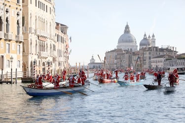 Personas vestidas de Papá Noel reman durantela  regata navideña en el Gran Canal de Venecia.