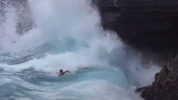 El surfista hawaiano Mason Ho remando para escapar de unas afiladas rocas contra las que está rompiendo una ola, en California (Estados Unidos).