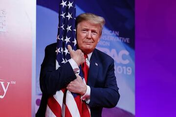 Donald Trump es captado abrazando la bandera estadounidense antes de subir al estrado para ofrecer una conferencia de prensa.