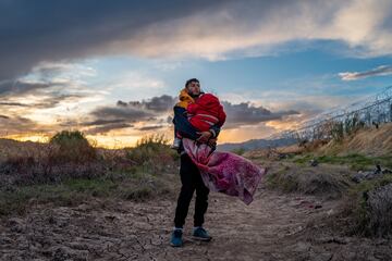 El migrante peruano Jordan y su hija de un año, Briana, esperan a su grupo de migrantes en preparación para cruzar a los EE. UU. el 26 de marzo de 2024 en El Paso, Texas. Hace cuatro días, cientos de migrantes que buscaban asilo se enfrentaron con guardias nacionales de Texas mientras esperaban para entregarse a agentes de patrulla fronteriza para su procesamiento. 