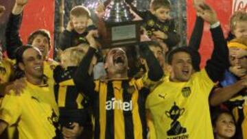 Los jugadores de Pe&ntilde;arol levantan la copa del campeonato uruguayo.