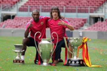 Carles Puyol y Eric Abidal posan junto a los trofeos conseguidos en la temporada 2010-2011: Supercopa de Espa?a, Champions y Liga.