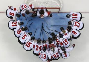 Las jugadoras del equipo de Canadá se reúnen alrededor de la red antes del inicio del juego de semifinales de hockey sobre hielo