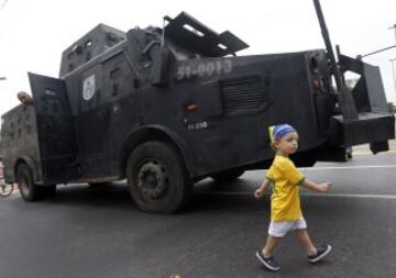 Un niño con la camiseta de Brasil camina frente a un vehículo blindado de la Policía en las inmediaciones del estadio de Maracaná, en Río de Janeiro, antes del partido de la final de la Copa Confederaciones entre las selecciones de Brasil y España.