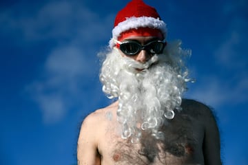 Un participante con gorro de Santa Claus, barba falsa y gafas de bucear, se prepara para saltar al agua en la 115ª edición de la Copa Nadal. 