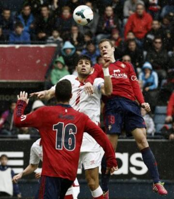 El delantero de Osasuna, Oriol Riera (d), y el defensa argentino del Sevilla, Federico Fazio (c), intentan conseguir la posesión del esférico.