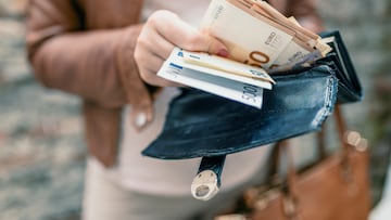 Woman holding in hands wallet with euro money. City girl is taking out money from wallet BILLETES BILLETE EURO EUROS