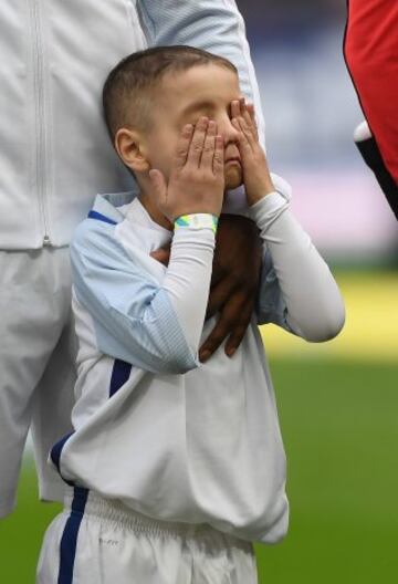 England mascot Bradley Lowery shields his eyes as the teams line up for the national anthems.