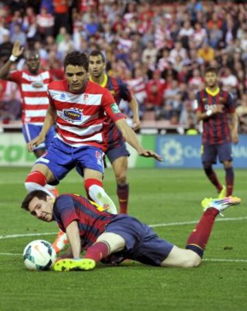 El delantero argentino del FC Barcelona Leo Messi (abajo) juega un balón desde el suelo ante el portugués Ilori, del Granada, durante el partido de Liga en Primera División que disputan en el estadio Nuevo Los Cármenes