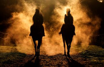 Esta bella y original imagen muestra las siluetas de dos caballos con sus respectivos jinetes entre la niebla y la penumbra propias de la caída de la tarde. Corresponde al momento en que los equinos regresan a los establos tras una jornada de entrenamiento en las instalaciones de la Cuadra Granary de Sam Drinkwaters, en Hereford (Reino Unido).