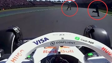 Dos comisarios cruzan la pista por delante de Liam Lawson.