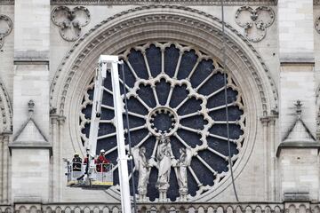  Varios bomberos trabajan en un elevador a la fachada de catedral de Notre Dame