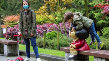 Un niño juega con una estatua de Mafalda situada en un parque de Oviedo bajo la tenta mirada de su madre.