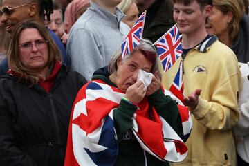 Una simpatizante monárquica se emociona esperando a que la familia real británica se asome al balcón del Palacio de Buckingham.