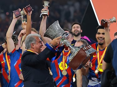 El presidente del FC Barcelona, Joan Laporta, celebra con el trofeo junto al equipo tras la conquista de la Supercopa de España.


