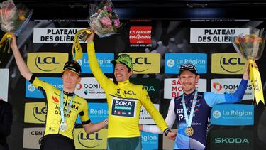 First-placed Team Bora's Slovenian rider Primoz Roglic wearing the overall leader's yellow jersey (C) celebrates his victory on the podium flanked by second-placed Team Visma's US rider Matteo Jorgenson (L) and third-placed Team Israel Premier Tech's Canadian rider Derek Gee (R) after the eighth and last stage of the 76th edition of the Criterium du Dauphine cycling race, 160,6km between Thones and Plateau des Glieres, near Thorens-Glieres, French Alps, on June 9, 2024. (Photo by Thomas SAMSON / AFP)