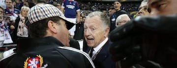 Lyon president Jean-Michel Aulas talks to fans on the pitch