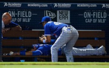 Munenori Kawasaki de los Toronto Blue Jays da un masaje en el banquillo a su compañero José Bautista durante el partido de beísbol contra los Atlanta Braves.