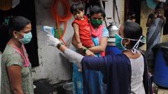 Una trabajadora del sistema de Salud toma la temperatura de un grupo de personas de un asentamiento irregular en el suburbio de Mankhurd, en el este de Bombay, India.