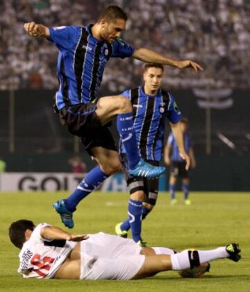 Lucas Simón salta la marca de Cristián Riveros de Olimpia. (arriba) Huachipato.